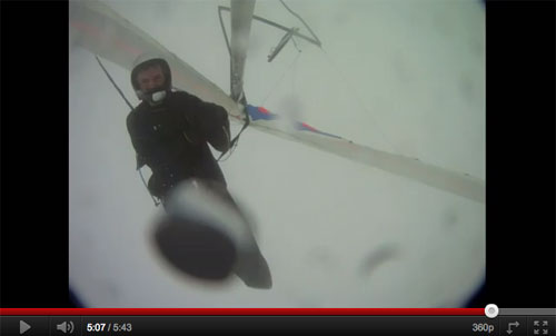 Looking remarkably composed, and with his hang glider flipped upside down, the pilot descends under reserve Looking remarkably composed, and with his hang glider flipped upside down, the pilot descends under reserve